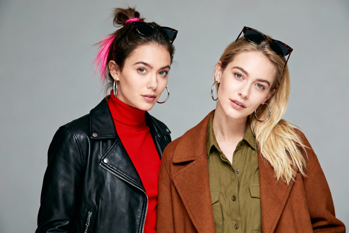 Two women posing together against a gray background